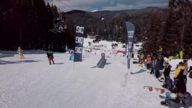 YAREMCHE, UKRAINE - 24 MARCH, 2018: Snowboarders & free ski riders take part in jib contest.Athletes grind on rail in Bukovel Snow Park.Extreme winter sport competition for young and active sportsmen.