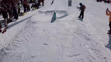 YAREMCHE, UKRAINE - 24 MARCH, 2018: Snowboarders & free ski riders take part in jib contest.Athletes grind on rail in Bukovel Snow Park.Extreme winter sport competition for young and active sportsmen.