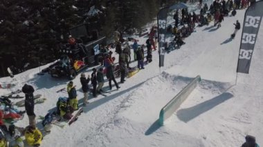 YAREMCHE, UKRAINE - 24 MARCH, 2018: Snowboarders & free ski riders take part in jib contest.Athletes grind on rail in Bukovel Snow Park.Extreme winter sport competition for young and active sportsmen.