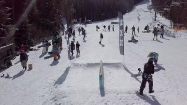 YAREMCHE, UKRAINE - 24 MARCH, 2018: Snowboarders & free ski riders take part in jib contest.Athletes grind on rail in Bukovel Snow Park.Extreme winter sport competition for young and active sportsmen.
