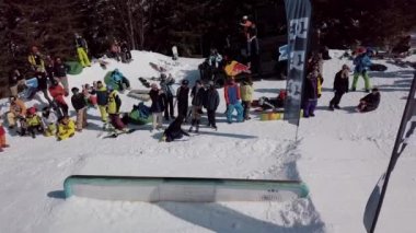 YAREMCHE, UKRAINE - 24 MARCH, 2018: Snowboarders & free ski riders take part in jib contest.Athletes grind on rail in Bukovel Snow Park.Extreme winter sport competition for young and active sportsmen.