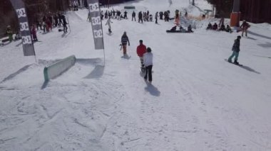 YAREMCHE, UKRAINE - 24 MARCH, 2018: Snowboarders & free ski riders take part in jib contest.Athletes grind on rail in Bukovel Snow Park.Extreme winter sport competition for young and active sportsmen.