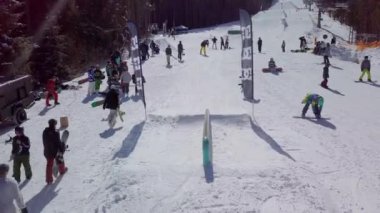 YAREMCHE, UKRAINE - 24 MARCH, 2018: Snowboarders & free ski riders take part in jib contest.Athletes grind on rail in Bukovel Snow Park.Extreme winter sport competition for young and active sportsmen.