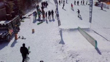 YAREMCHE, UKRAINE - 24 MARCH, 2018: Snowboarders & free ski riders take part in jib contest.Athletes grind on rail in Bukovel Snow Park.Extreme winter sport competition for young and active sportsmen.