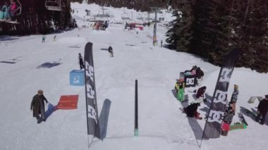 YAREMCHE, UKRAINE - 24 MARCH, 2018: Snowboarders & free ski riders take part in jib contest.Athletes grind on rail in Bukovel Snow Park.Extreme winter sport competition for young and active sportsmen.