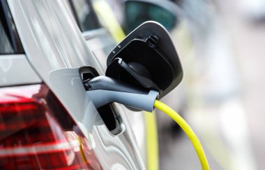 Elektrikli otomobil park pille sarı kablo ile şarj moden. Aracınızın yeni binmek için elektrik enerjisi ile şarj edin. Hava kirliliği ile ekolojik şehir ulaşım 