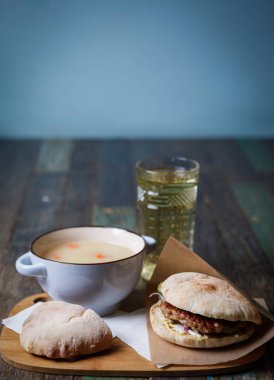 Geleneksel Sırp fast food restoran yiyecek. Kaymaklı çorba, ahşap rustik masa tabakta servis huysuz topuz ekmek taze et burgeri. Egzotik Cafe gıda arka plan   