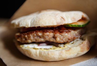 Huysuz topuz dekoratif kahverengi kağıt geleneksel Sırp Pljeskavica hamburger ızgara sığır eti, füme peynir dilimi ve sebze sos ile servis. Fast food restoran yemek yakın çekim   
