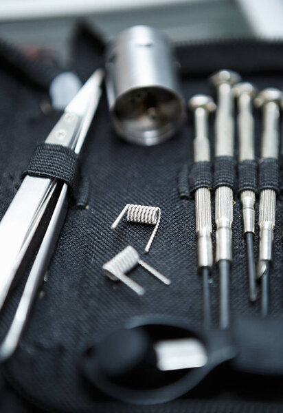 Vape shop.Modern vaping device maintenance & upgrade parts in close up.Buy popualr ecig vaper device.Electronic cigarette gadget for smoking ejuice.Screwdrivers tool kit for repair