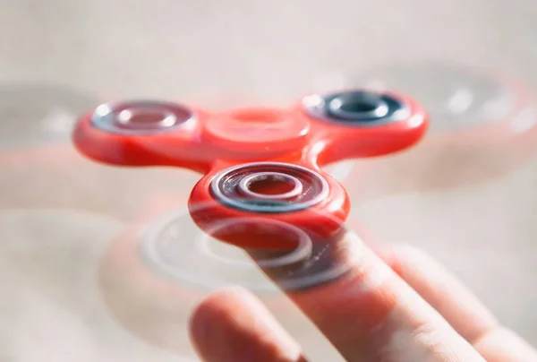 Boy play with modern finger spinner gadget.Popular fidget spinner device on bearings to play balance game & improve reaction.Trendy portable spinning toy in male hand