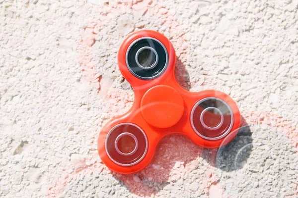 Super popular finger spinner fidget device.Modern red plastic spinning toy with bearings.Play with spinners to improve reaction & learn new cool tricks.Trendy new spinner gadget close up