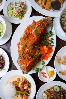 Egzotik Vietnam gıda restoran menü kapatın. Geleneksel Asya yemeği beyaz tabakta. Kızarmış ve dilimlenmiş taze sebze ile servis deniz yiyecek lezzetli sazan balık 