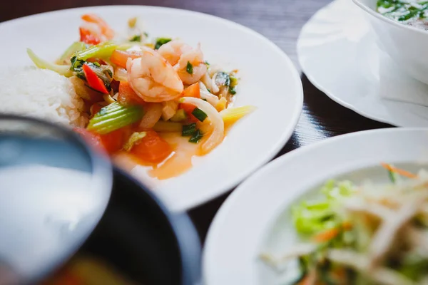 Big tasty Asian dinner with seafood & spring rolls.Fried crispy shrimp rolls & springrolls on white plate served with fresh vegetables salad.Colorful exotic Vietnamese cuisine close up