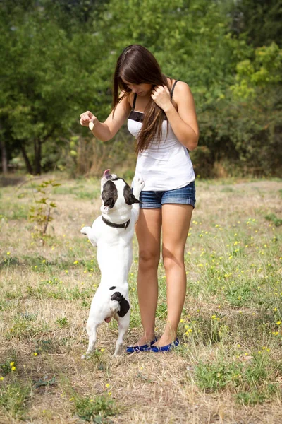 黑发少女与她健康的年轻斗牛犬在公园里玩 — 图库照片