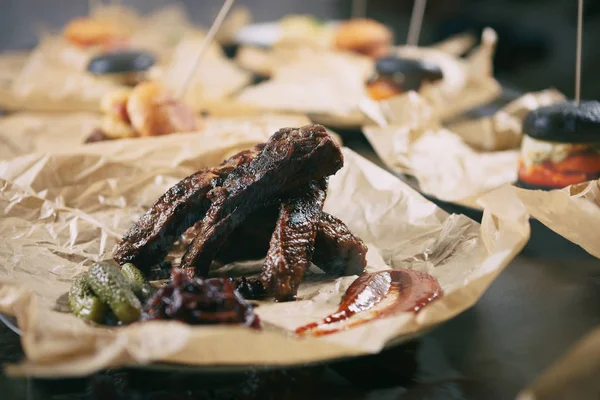 Delicious smoked ribs with sauce & pickled cucumber in fast food restaurant menu. Tasty bun unhealthy fat fried meat food close up.