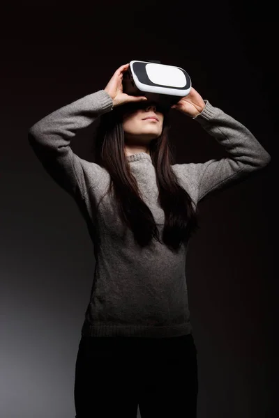 Young girl playing mobile game app on virtual reality headset device.Modern VR box for mobile gaming.Portable vr glasses technology for gamers.Augmented reality gadget to play moblie games