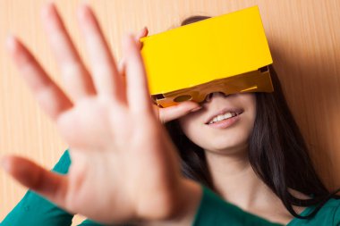 Çekici genç kız karton sanal artırılmış gerçeklik kulaklık ile vr video oyunu oynuyor. Popüler teknoloji, hipster renkleri. Akıllı telefonda mobil oyun için Vr gözlükler. Pretty genç oyuncu kız oyna. 