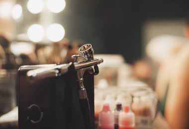 Airbrusher için profesyonel makyaj stüdyo daimi bir visagiste tablo. Kozmetik ve arka planda fırçalar. Modern hipster renkleri