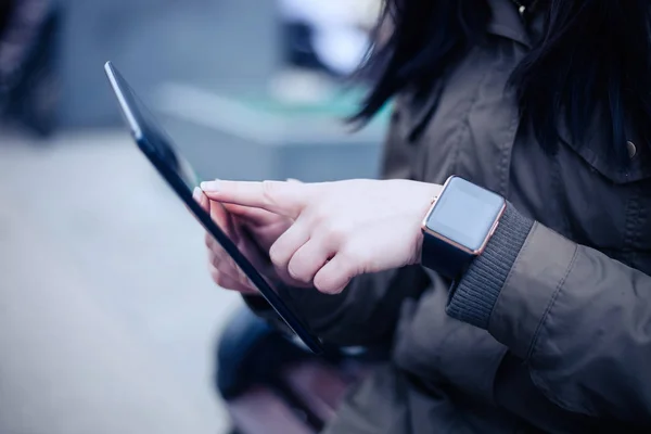 女性は彼女の手首のスマートな腕時計を着用しながらタブレット を使用して この新しいデバイスでは常にあなたが欲しいどこかからインターネットと社会的なメディア ネットワークに接続を維持します — ストック写真