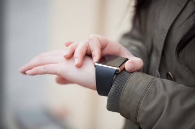 Bilek üzerinde akıllı saatini dokunmadan parka genç kız. Bu yeni becerikli alet her zaman internet ve sosyal medya ağları ile istediğiniz yerden bağlı kalmak sağlar.