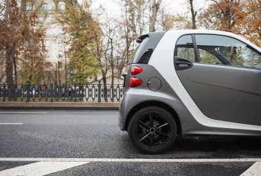 Küçük elektrikli araba şehir sokak Park. Sonbahar günü, soğuk sezon. Temiz elektrik şehir ulaşım aracı binmek. Elektro motor ile açık kentsel tranpsort 
