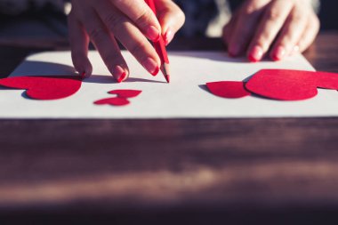 Kırmızı penicl bir aşk mektubu St.Valentines gününde kırmızı kalp boş beyaz kağıt yazma ile eller kağıttan yapılmış resimler şeklinde. Boşaltmak çok 