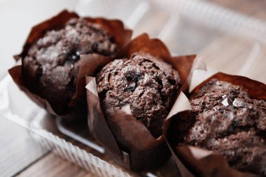 Kafede lezzetli çikolatalı kekler. Beyaz ahşap masa üzerinde dekoratif kağıt üç taze çikolatalı kek. Metni yerleştirmek için alanı kopyalama,odağı kapatma. 