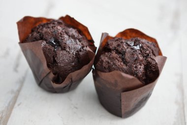 Kafede lezzetli çikolatalı kekler. Beyaz ahşap masa üzerinde dekoratif kağıt üç taze çikolatalı kek. Metni yerleştirmek için alanı kopyalama,odağı kapatma. 