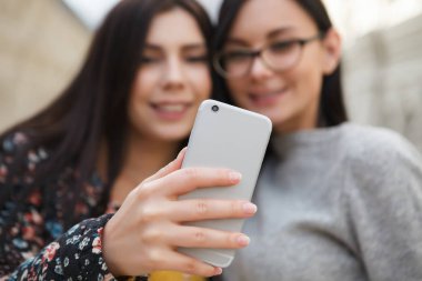 Selfie büyük modern gümüş akıllı cep telefonu ile alışveriş merkezinde alarak iki çekici genç kadın. Mutlu beyaz kızlar, yeni smartphone aygıtı
