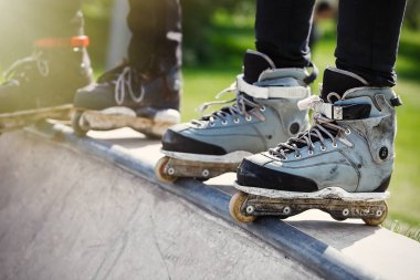 Açık skate Park beton rampa tepesinde duran agresif inline paten giymiş rollerbladers metrelik. Silindir bıçakları için hile ve biler giyen aşırı spor atlet