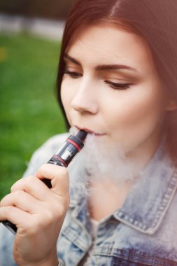 Genç vaper kız yasaktır gliserin e-suyu ya da e-sıvı trendy e-cig vaping cihazı ile portresi. Nikotin, vape güvenli bir şekilde sigara içme. Güzel beyaz kadın modeli 
