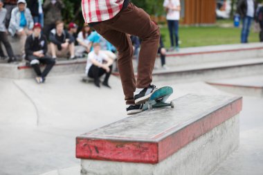 Kaykaycı çocuk üzerinde bir çıkıntı açık skate Park taşlama. Arka planda, gençlik spor yarışmalarının kalabalık. Popüler aşırı spor, tehlikeli hüner. Kaykay üzerinde odaklanmak 