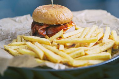 Delicious büyük yağlı fast food restoran menü kahverengi dekoratif kağıt üzerinde hizmet hamburger hazırlanmış. Lezzetli, ama kafede plaka sağlıksız abur cubur yağlı et, sos ve patates kızartması ile