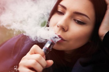 Sigara nikotin çıkın, vaping e-suyu, e-sıvı başlar. Buharlaştırıcı aygıt, Sigara içenler için modern aracı kullanan genç ve güzel kadın. Güvenli ve lezzetli gliserin buharı