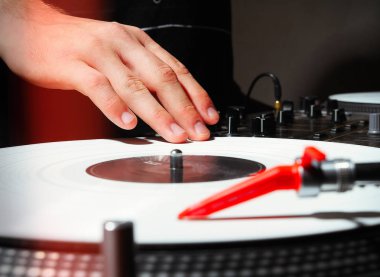 Bir Dj pikap karanlık stüdyo ya da gece kulübü içinde beyaz vinil birlikte müzik el. Profesyonel analog ses ekipmanları