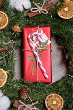 Güzel Noel ve yeni yıl hediye kutu paket. Kırmızı dekoratif küçük hediye Noel sopa ve dekoratif çam köknar ağacı çelenk dışında süslenmiş. Ek yükü dikey portre vurdu