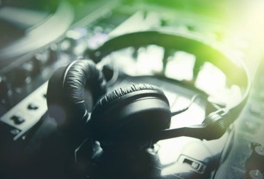 Gece kulübünde Konser sahnesinde profesyonel ses karıştırıcı aygıt üzerinde büyük siyah Dj kulaklık. Parlak yeşil sahne ışıkları. Yüksek kaliteli kulaklık müzik dinlemek. Edm disk jokey için Pro ses ekipmanları