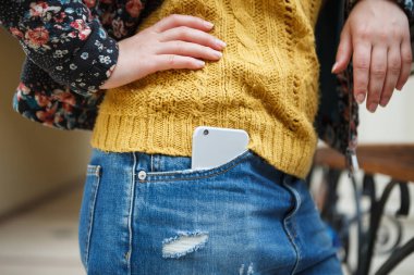 Trendy akıllı cep telefonu genç moda kız kot pantolon cebinde. Büyük gümüş smartphone, popüler yeni gadget modeli.