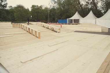 Skatepark montaj, kurulum süreci açık havada. Dışarıda paten parkı inşa etmek. Öğütme raylı, grindbox ve ahşap atlama yarıçapı. Kaykay, silindir bıçakları, Bisiklet pateni için ahşap konstrüksiyon.
