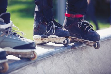 Açık skate Park beton rampa tepesinde duran agresif inline paten giymiş patenci ayakları. Silindir bıçakları için hile ve biler giyen aşırı spor atlet