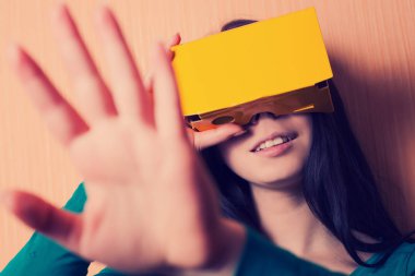 Genç kız akıllı telefonuna bağlı karton sanal gerçeklik kulaklık ile video oyunları oynarken