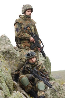 Askeri yardım. Ordu takım çalışması. Savaş üniforması içinde Ukraynalı ordunun kamuflajında silahlı askerler. Soldier takım üyesi tırmanmaya kaya açık yardımcı olur. Savaş Doğu Ukrayna. Heavy mühimmat, otomatik tüfek
