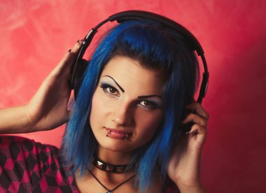 Güzel genç kız Dj boyalı mavi saçlı, dudak piercing ve yaka ile kulaklıklar giyen spykes. Disk jokey veya ses meraklısı için ses antremanı