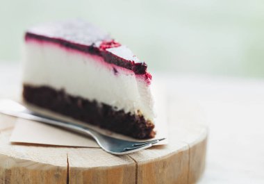 Lezzetli ahududu peynir pastasından bir tahta üzerinde geç bir kafede çatal ile görev yaptı. Lezzetli pasta - krem, çilek ve taze bisküvi. Makro fotoğraf kadar kapatın. 