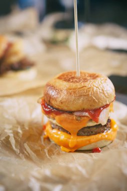 Lezzetli büyük şişman hazırlanmış hamburger pastırma dilimi, ketçap ve füme peynir ile fast food restoran menüsünde kağıt tabakta servis. Abur cubur yemek kafede kapatın. Amerikan Burger