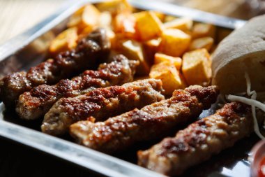 Geleneksel Sırp kavrulmuş et yemek ile kızarmış patates servis. Fast food restoran menüsünde egzotik ızgara biftek. Şişman füme çanak arka plan yakın çekim.
