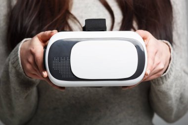Mobil oyun uygulama için modern sanal gerçeklik gözlük tutan kadın. Mobil app kullanın, video oyun üstünde belgili tanımlık gitmek. Yakın çekim, el içinde vr kulaklık odaklanmak. Trendy yeni augmented reality gaming aygıt