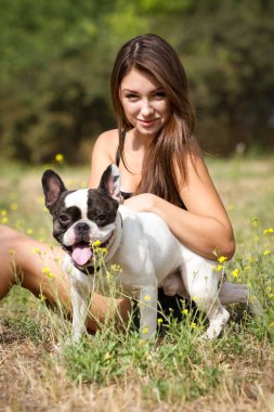genç esmer kız parkta onun sağlıklı genç bulldog ile oynarken