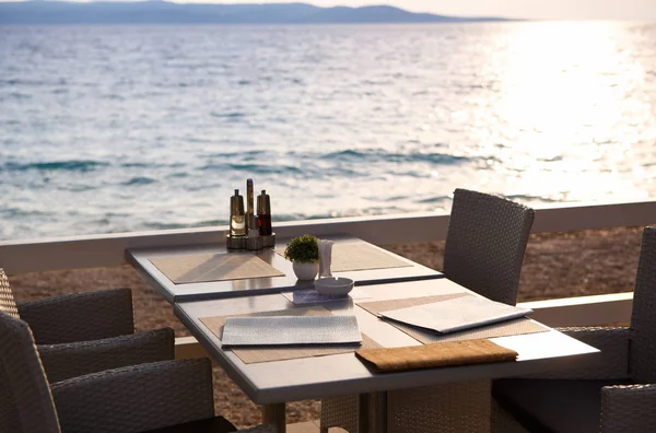 Beautiful summer beach restaurant on Adriatic Sea coast.Enjoy meal in cozy cafe on Croatian Riviera.Travel destination for holiday travel.Sunset light sparkle on sea waves