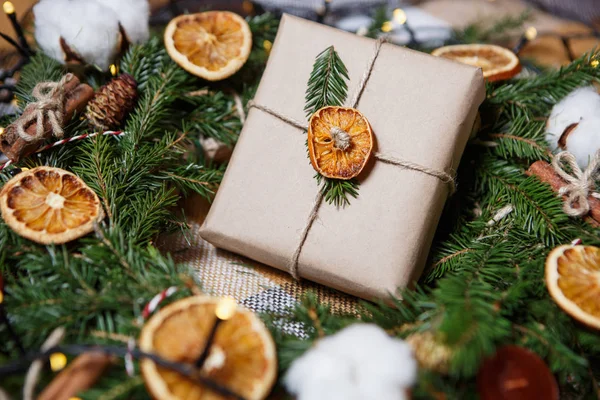 壮大な手作りクリスマス ギフト ボックス 美しい新年プレゼント包装乾燥オレンジとシナモンで装飾されたパイン ツリー花輪で横になっている装飾的な茶色の紙に包まれました — ストック写真